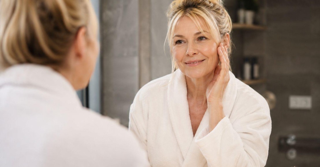 Femme de 50 ans en peignoir dans sa salle de bain