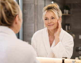 Femme de 50 ans en peignoir dans sa salle de bain